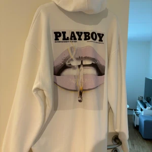 Vit hoodie från Playboy x Missguided - Säljer en vit oversized hoodie från Playboy x Missguided. Framsidan har en liten lila Playboy-logga och baksidan har ett stort tryck med läppar och texten PLAYBOY. Hoodien har känguruficka och luva. Är nästan aldrig använt bara hängt i garderoben