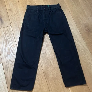 Svarta raw g-star - Säljer ett par svarta jeans med rak passform. Klassisk femficksmodell med knapp och dragkedja i gylfen. Byxorna har bälteshällor och är tillverkade i ett kraftigare jeanstyg. Perfekta för en stilren och enkel look.