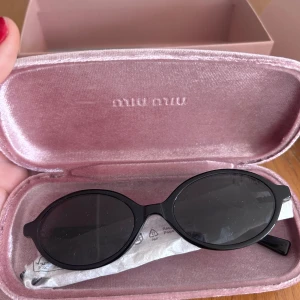 Svarta solglasögon från Miu Miu - Snygga svarta solglasögon från Miu Miu med rundade bågar och diskret logga på skalmen. Kommer i ett rosa fodral. Perfekt accessoar för att lyfta din stil. Helt nya då jag fick dubbletter!  
