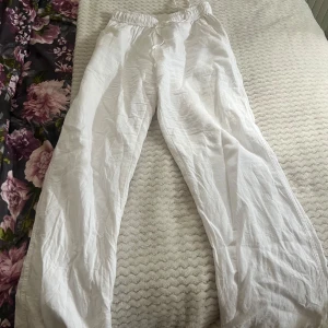 Vita linnebyxor med resårmidja - Säljer ett par vita linnebyxor med avslappnad passform och resår i midjan från Nelly. Byxorna har raka, vida ben och är perfekta för varma dagar. Lätta och luftiga, passar till många olika stilar. Jag har max använt de 2 gånger 