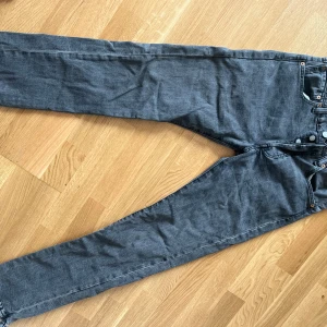 Levi's 501 grå jeans - Säljer ett par klassiska Levi's 501 jeans i grå tvätt. De har raka ben, fem fickor och knappgylf. Jeansen har den ikoniska läderpatchen bak och är tillverkade i slitstark denim. Perfekta för dig som gillar en tidlös och avslappnad stil.
