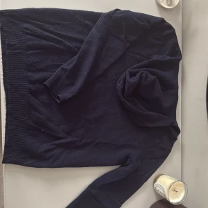 Mörkblå hoodie i kashmir från Soft Goat - Säljer en mörkblå hoodie från Soft Goat i 100% kashmir. Tröjan har långa ärmar, ribbade muddar och en huva. 