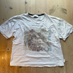 Vit Art Nouveau t-shirt från nu-in - Vit t-shirt från nu-in med Art Nouveau-tryck i alla möjliga färger på framsidan. Klassisk rund hals och korta ärmar. Materialet är bomull. Inte alls använd mycket. Sitter ganska kroppat och är riktigt snygg. Nypris är 800kr. Skriv vid intresse!
