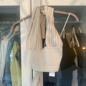 Halterneck topp glittrig - Halterneck topp från Gina Tricot, aldrig använd (prislapp kvar). Glittrigt och plisserat material. Knyts i nacke och bakom ryggen så passar flera storlekar. 