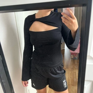 Svart långärmad topp med twistad detalj - Snygg svart långärmad topp med en twistad detalj vid halsen och en öppen del över bröstet.