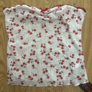 Vit tubtopp med körsbärsmönster - Söt vit tubtopp med röda körsbär över hela tyget och en liten röd rosett framtill.