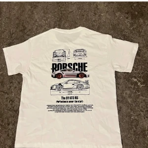 Vit Porsche 911 GT3 RS t-shirt - Vit t-shirt med coolt Porsche 911 GT3 RS-tryck på ryggen. Grafiska bilskisser och text i svart, samt en detaljerad bild av bilen med röda fälgar. Rund hals och korta ärmar, perfekt för dig som gillar bilar och motorsport. Materialet känns som mjuk bomull.