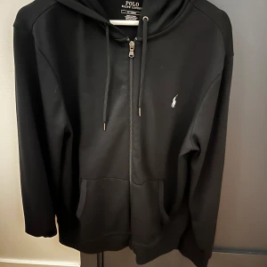 Svart hoodie från Polo Ralph Lauren - Svart zip  hoodie från Polo Ralph Lauren med dragkedja och huva. Använd en gång för provning, köpte fel storlek och har glömt att byta. Kvitto finns! 