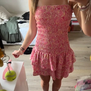 Rosa smockklänning med volang - Supersöt tubklänning från Gina tricot i storlek S, med smockad överdel och dubbla volanger nedtill. Klänningen har ett mönster i rosa, beige och ljusgult. Perfekt för dig som gillar färg och mönster! Materialet är mjuk bomull som känns skönt mot huden. Perfekt för sommar eller vår 💕🤍💛