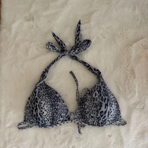 Leopardmönstrad bikini från Andy by Frank Dandy - Snygg bikiniöverdel med leopardmönster i svart och grå toner från Andy by Frank Dandy. Modellen har trekantskupor och knyt både i nacken och ryggen för perfekt passform. Materialet är mjuk polyester med elastan som ger bra stretch och komfort.