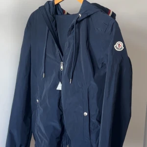 Moncler Windbraker (Size 1) - Hej, nu säljer vi denna snygga vind jacka som passar perfekt till lite mer kyliga väderförhållanden,                                         Moncler windbraker, i storlek 1, vilket motsvarar en S i vanliga jackor, jackan är lätt använd, i skick 9/10, jackan Sitter relativt bra på mig, (63 kg, 177cm). Vi skickar ut den så fort köparen är redo samma dag. Vid en smidig deal kan priset diskuteras! 👍