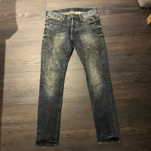 Blå jeans från Denim - Säljer ett par blå jeans från Denim med snyggt slitna detaljer och klassisk femficksdesign. Jeansen har normal midja. Materialet är robust jeans och färgen är mörkblå med ljusare tvättade partier. Jeansen har även en sällsynt tvätt! Skriv vid frågor eller funderingar. 