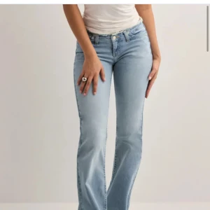 Oanvända Bootcut ljusblå jeans - Helt oanvända! Snygga ljusblå bootcut jeans med klassisk femficksdesign och normal passform. Jeansen har en högre midja och är tillverkade i mjukt denimtyg som ger en skön känsla. Perfekta för dig som gillar retrovibbar och vill ha ett par jeans med lite extra attityd. 