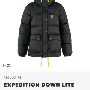 Svart dunjacka från Fjällräven - Säljer en svart Expedition Down Lite dunjacka från Fjällräven med gula detaljer och klassisk logga på bröstet. Jackan har stora fickor framtill, dragkedja och knappar, samt justerbar huva. Perfekt för kalla dagar och riktigt snygg streetstil.