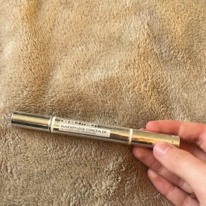 Perfect Match concealer med borste - Säljer en Perfect Match Augenpflege-Concealer med inbyggd borste. Tuben är silverfärgad och har en praktisk applikator för enkel användning. Färgen är ljusbeige och passar för att täcka mörka ringar under ögonen. Innehåller hyaluronsyra för extra vård.