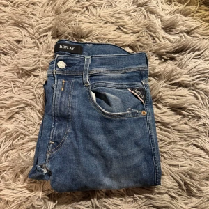 Replay anbass hyperflex  - Blå jeans från Replay Hyperflex med klassisk femficksdesign och snygga kontrastsömmar. Jeansen har en normal passform och är tillverkade i stretchigt jeansmaterial för extra komfort. Märkespatch bak i midjan och Replay-logga vid fickan. Perfekt för dig som gillar stilrena och bekväma jeans.W31 L32. Den ända defekten som finns är den där byxbenen möts. Bara att höra av sig vid minsta intresse!
