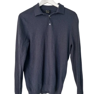 Mörkblå polotröja från Massimo Dutti - Snygg mörkblå polotröja från Massimo Dutti i mjuk ull och kashmirmix. Tröjan har klassisk krage, två knappar framtill och långa ärmar. Perfekt för dig som gillar stilrena och bekväma plagg med lite lyxig känsla.