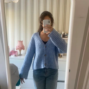 Ljusblå ribbad kofta med knappar från hm - Supermysig ljusblå kofta med ribbad struktur och tre stora knappar framtill. Koftan har en v-ringad hals och långa ärmar med lite loose passform. Perfekt att slänga på över ett linne eller t-shirt. Stickad i mjukt material som känns skönt mot huden.