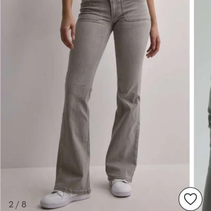 Grå bootcut jeans med hög midja - Snygga grå jeans med bootcut passform och hög midja. Jeansen har klassiska fickor både fram och bak samt en stilren look som passar till sneakers. Materialet är jeans och färgen är en neutral gråton som är lätt att matcha med olika outfits.