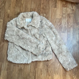 Beige pälsjacka från VILA - Säljer en fluffig och mjuk pälsjacka i fuskpäls från VILA i beige ton där. Pälsen har ”struktur” och dess utseende är alltså inte tecken på användning. Jackan stängs med dolda tryck-knappar framtill. Storlek 38. Använd fåtal gånger.
