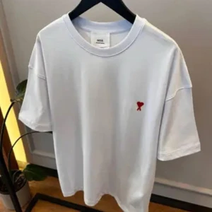 Vit Ami t-shirt med rött hjärta - Vit t-shirt från Ami Alexandre Mattiussi med klassisk passform och rund hals. På bröstet finns ett broderat rött hjärta med bokstaven A. Väldigt fin och fräsch t-shirt.