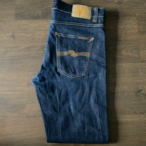 Mörkblå jeans från Nudie Jeans - Säljer ett par riktigt fräscha och stilrena jeans från nudie i utmärkt skick, inga defekter eller liknande utan felfria. Passar perfekt till allt och en otroligt snygg mörk färg som enligt mig är extra snygg, skriv privat vid minsta fundering🙌🏻👌🏻