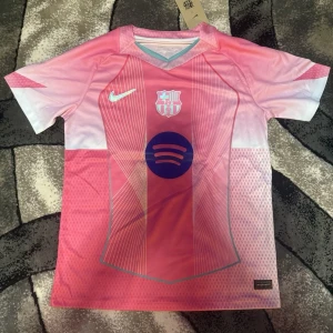 Barcelona Lamine Yamal rosa matchtröja - Snygg Barcelona fotbollströja med Lamine Yamal och nummer 10 på ryggen. Tröjan är rosa med ljusblå detaljer och har ett grafiskt mönster framtill. Nike-logga och Spotify-sponsor på bröstet. Kortärmad och tillverkad i lätt, ventilerande material.