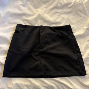 Svart kortkjol från SHEIN - Stilren svart kortkjol från SHEIN med två fickor fram. 