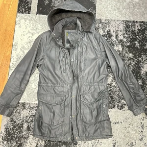 Jack & jones vinterjacka  - Snygg svart vinterjacka från Jack & Jones med huva och flera praktiska fickor. Jackan har en dragkedja och knappar framtill samt en mjuk insida för extra värme. Perfekt för kyligare dagar.