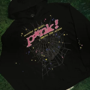 Sp5der hoodie - Cool svart hoodie med en unik spindelnätsdesign och texten 'nevermind the spider, here's the slime' i rosa och gult. Perfekt för en avslappnad stil med en touch av humor och kreativitet.