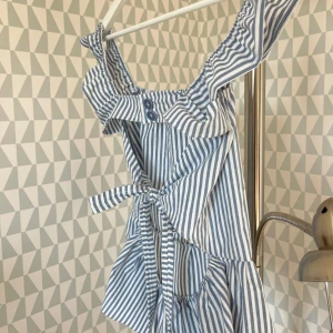 randig blus  - ljusblå randig somrig topp. knytning i ryggen och knappar ovanför:). Skulle säga att strl är XS/S. Möjligen M beroende på byst :) Har sytt den själv💞