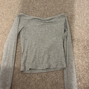 Grå långärmad topp - Säljer en stilren grå långärmad topp i mjukt material. Perfekt för en avslappnad look. Toppen har en enkel design och är lätt att matcha med olika outfits.
