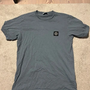 Stone Island t-shirt - Säljer en snygg blå t-shirt från Stone Island med deras ikoniska logga på bröstet. Perfekt för en avslappnad stil. T-shirten är kortärmad och gjord i mjukt material. Nypris 1200 mitt pris 299.