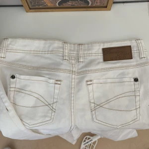 Vita jeansbyxor från Esmara - Snygga vita jeans från Esmara med klassisk femficksdesign och kontrasterande sömmar. Byxorna har en knapp och dragkedja framtill samt en liten broderad detalj vid fickan. Priset går absolut att diskutera!!🥰🥰