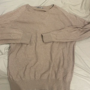 Beige stickad tröja från J.Lindeberg - Säljer en stilren beige stickad tröja från J.Lindeberg. Tröjan har långa ärmar och ribbade muddar vid ärmslut och nederkant. Perfekt för kyligare dagar.