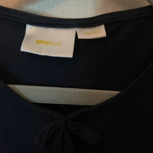 Mörkblå blus från Gina Tricot - Säljer en söt mörkblå blus från Gina Tricot med puffiga korta ärmar. Blusen har en volangdetalj vid nederkanten som ger en fin siluett. Perfekt för en stilren look!