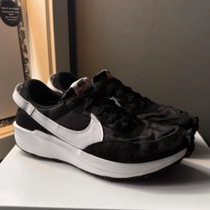 Nike runner shoes - Snygga svarta sneakers med vita detaljer från Nike. Skorna har en klassisk design med snörning och en bekväm sula. Perfekta för både vardag och träning.