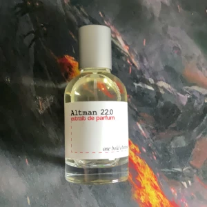 Altman 22.0 Extrait de Parfum - Säljer en exklusiv Altman 22.0 Extrait de Parfum. Flaskan har en minimalistisk design med en vit etikett och röd text. Den har en rund form och ett grått lock. Perfekt för den som söker en unik doftupplevelse. 