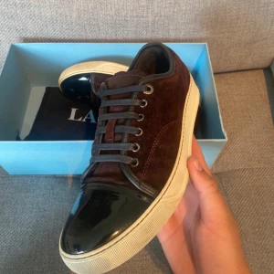 Lanvin skor - Ett par sällan använda lanvin sneakers i fint skick. Vinröd/brun färg. Box och dustbag medföljer. Pris får att diskutera. Storlek 41.