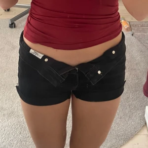 Svarta jeansshorts från ONLY - Snygga svarta jeansshorts från ONLY med klassisk femficksdesign och knappgylf. Perfekta för en avslappnad stil. De är midwaist men man kan vika ner mudden så de blir Lågmidjade och är tillverkade i ett slitstarkt denimtyg.