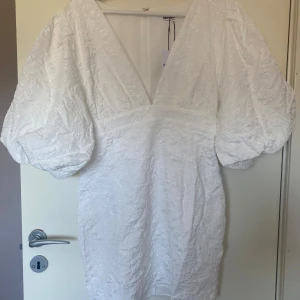 Studentklänning/vit klänning från Showpo - Säljer en ursnygg studentklänning/vit klänning med djup v-ringning och puffiga ärmar. Alldeles ny, från Showpo med prislapp kvar. Finns i storlek 36/S men även 38/M, normal i storlek.