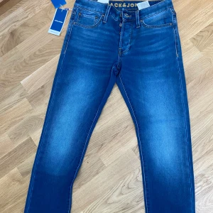 Blå jeans från Jack & Jones - Snygga blå jeans från Jack & Jones i modellen Glenn i nytt skick. De har en slim passform och är tillverkade i ett mjukt denimtyg. Byxorna har klassisk femficksdesign, perfekta för en stilren look. Priset kan diskuteras.