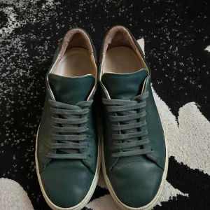 Gröna Axel Arigatos - Snygga gröna sneakers i skinn med snörning. Perfekta för en avslappnad stil. De har en vit sula som ger en fräsch kontrast till det gröna lädret.