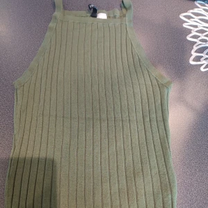 Olivgrön ribbad linnetopp från Divided storlek xs - Säljer en stilren olivgrön ribbad linnetopp från Divided. Toppen har en enkel design med smala axelband och är perfekt för varma dagar. Den är tillverkad i ett mjukt och stretchigt material som ger en bekväm passform.