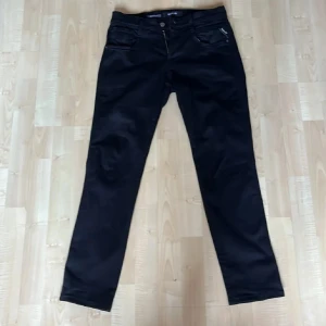 Svarta jeans från Replay - Snygga svarta jeans från Replay Hyperflex Anbass med dragkedja och knapp. De har en klassisk femficksdesign och är perfekta för en stilren look. Passar bra till både vardag och mer uppklädda tillfällen.
