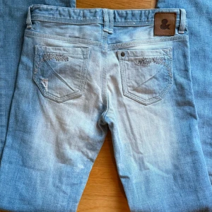 Ljusblå jeans med broderade detaljer - 💞Fri frakt finns💞Lågmidjade jeans med snygg Wash! Står storlek 28 men små i storleken!! Passar ungefär 26 skulle ja säga💞vill sälja snabbt då ja är i behov av pengar 
