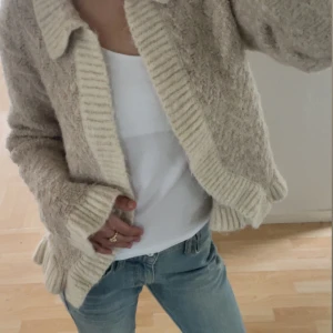 Beige stickad kofta - Mysig beige stickad kofta med krage och ribbade detaljer från Zara i stil XS, använd ett fåtal gånger💗