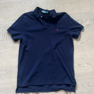 Mörkblå pikétröja från Ralph Lauren - Marinblå pikétröja från Ralph loren i storlek M. Skick 9/10 då tröjan  är nästintill som ny/skriv dm gällande frågor