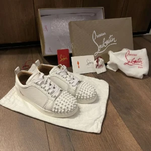 Vita sneakers från Christian Louboutin - Snygga vita sneakers från Christian Louboutin med  nitar. Skorna har snörning och är tillverkade i skinn. Hör av er vid frågor🤍