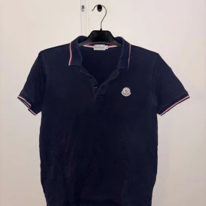 Mörkblå pikétröja från Moncler - Säljer en stilren mörkblå pikétröja från Moncler inte andvänt mycket och säljer den för ett superpris, ställ gärna frågor och priset är inte hugget i sten🌟